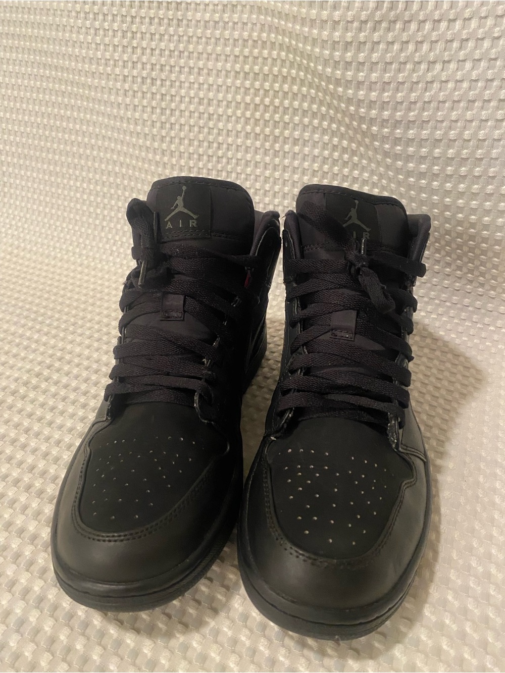 Nike Air Jordan 1 Mid All Black with suede material. Tear on top of shoe shown^